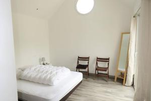 a white bedroom with a bed and two chairs at Maison neuve de plain-pied à 100m de la mer et 200m du Coz-Pors à TREGASTEL - Ref 71 in Trégastel