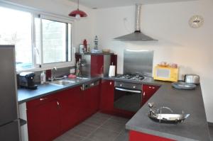 a kitchen with red cabinets and a counter top at Maison neuve de plain-pied à 100m de la mer et 200m du Coz-Pors à TREGASTEL - Ref 71 in Trégastel +10 photos