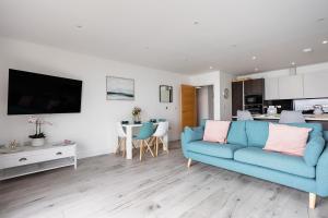 a living room with a blue couch and a kitchen at The Bay in Sandown