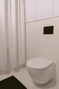 a white toilet in a white bathroom with curtains at Alfreda in Sokołowsko