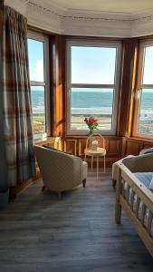 a room with a bed and a couch and windows at The Cairns Leven in Fife