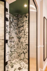 a bathroom with a shower with a stone wall at Hôtel Chamar in Paris