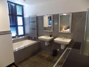 a bathroom with two sinks and a bath tub and a mirror at Vakantiewoning Hartje Maaseik in Maaseik