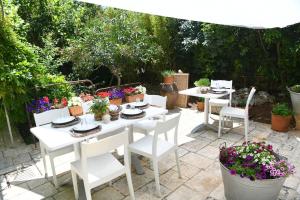 B&B Masseria Piccola في تْشيستيرنِنو: طاولة بيضاء مع كراسي بيضاء ونباتات الفخار