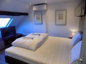 a bedroom with a large white bed and a television at Vakantiewoning Hartje Maaseik in Maaseik