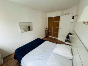 um quarto com uma cama branca e um cobertor azul em Appartement spacieux centre-ville em Caen