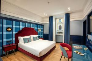 a hotel room with a bed and a red chair at The Independent Hotel in Rome