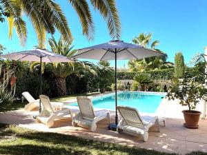 a group of chairs and umbrellas next to a swimming pool at Maison cosy en bordure du golf. in Saint-Raphaël