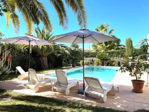 um grupo de cadeiras e guarda-sóis ao lado de uma piscina em Maison cosy en bordure du golf. em Saint-Raphaël