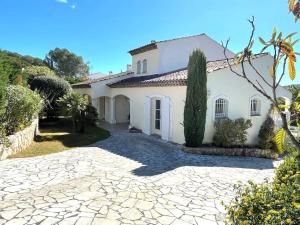 a large white house with a stone driveway at Maison cosy en bordure du golf. in Saint-Raphaël