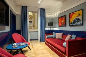 a living room with a red couch and red chairs at The Independent Hotel in Rome