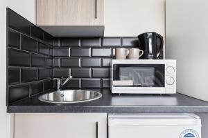 a kitchen counter with a sink and a microwave at Serviced Modern Studio in Harrow HA3 London - 4 in Harrow