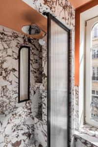 y baño con pared de piedra y ducha acristalada. en Hôtel Chamar, en París