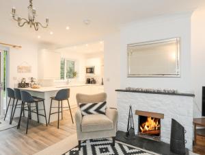a living room with a fireplace and a kitchen at 15 Maes Awel in Pwllheli