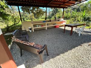 un patio con mesa, sillas, mesa y banco en Cabina La Pina, en Puerto Jiménez