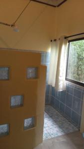 baño con ventana y azulejos azules en Cabina La Pina, en Puerto Jiménez