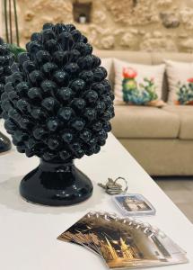 a black vase filled with balls on a table at Tannur Del Carmine in Noto