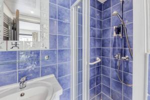 W wyłożonej niebieskimi kafelkami łazience znajduje się umywalka i prysznic. w obiekcie Bel appartement avec WIFI et terrasse à PERROS-GUIREC - Réf 815 w mieście Perros-Guirec