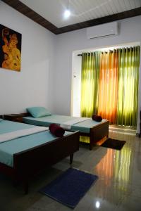 2 camas en una habitación con cortinas verdes y naranjas en Green Bird Villas en Kandy