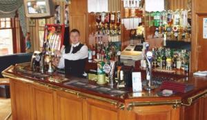 un hombre parado detrás de un bar en un pub en OYO Dunmar House Hotel, en Alloa