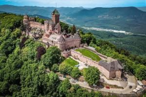 un castillo en la cima de una colina con coches en B&B Chambre Privative Chez L'habitant Sur La Route Des Vins Parking Box vélo en Issenheim