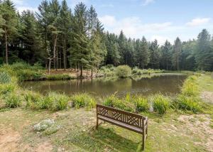 a park bench sitting in front of a pond at Remarkable 3-Bed Lodge in Honiton in Honiton