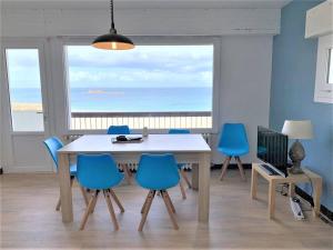 uma sala de jantar com uma mesa e cadeiras azuis em Appartement 2 chambres avec superbe vue mer sur la plage de Trestrignel à PERROS-GUIREC - Réf 834 em Perros-Guirec