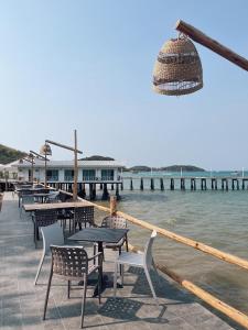 Rimtalay Resort Koh Larn في كو لان: صف من الطاولات والكراسي بجانب الماء