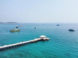 a dock in the middle of the water with boats at Rimtalay Resort Koh Larn in Ko Larn