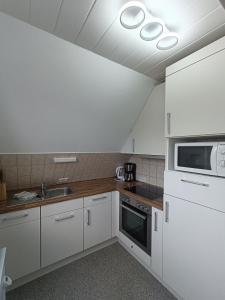 a kitchen with white cabinets and a microwave at LütjeFöhr in Alkersum