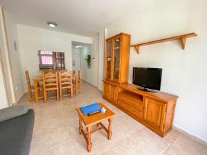 a living room with a television and a table at Apartamentos Madeira 3000 in Alcossebre