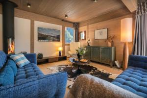 a living room with blue couches and a fireplace at Chalet Ours Rouge - OVO Network in Le Grand-Bornand