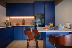 a kitchen with blue cabinets and a counter with chairs at Chalet Ours Rouge - OVO Network in Le Grand-Bornand +30 photos