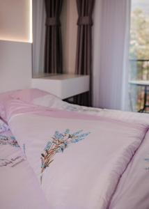 Una cama con una manta blanca con flores azules. en Nil's Apartments, en Peje