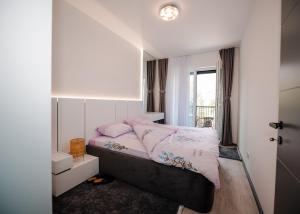 1 dormitorio con cama con sábanas rosas y ventana en Nil's Apartments, en Peje