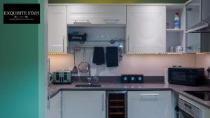 a kitchen with white cabinets and a sink at Exquisite, 2 bed apartment with free parking! in Coventry