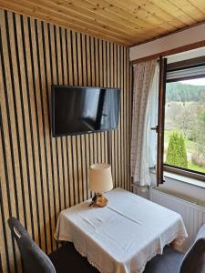 a room with a table and a television on a wall at Am Wehrastrand App 5 in Todtmoos