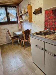 a kitchen with a sink and a table with chairs at Am Wehrastrand App 5 in Todtmoos