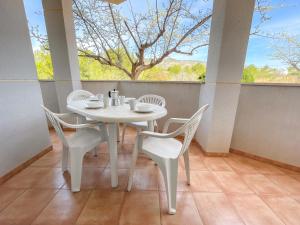 una mesa blanca y sillas en un porche con ventana en Apartamentos Neptuno 3000 en Alcossebre