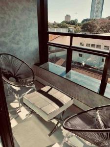 a balcony with a table and chairs and a window at Loft moderno e Hi- tech Vertigo in Campo Grande