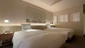 two beds in a hotel room with white sheets at Hotel Anaga in Minamiawaji