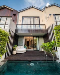 a house with a swimming pool in front of a house at Sunny Village Berawa in Canggu