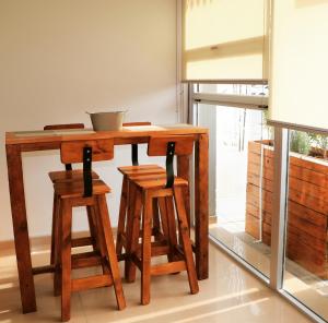 a wooden table with two stools and a bowl on it at Sureño in Puerto Pirámides