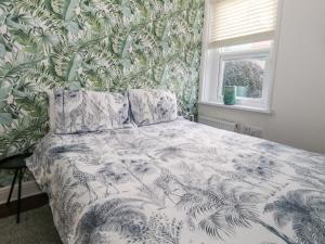 a bedroom with a bed with a leafy wallpaper at Monaloe in Weymouth