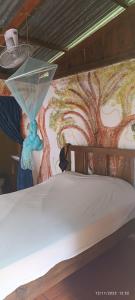 a bed with a painting on the wall at Hostel La Gloria in Ometepe