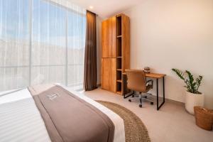 a bedroom with a bed and a desk and a window at Sunny Village Berawa in Canggu
