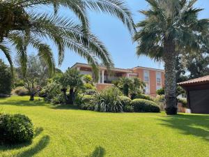 een grote tuin met palmbomen en een gebouw bij VILLA VUE MER in Pietrosella