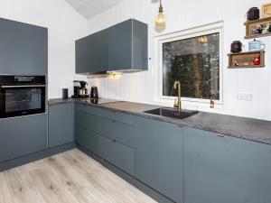 een keuken met blauwe kasten, een wastafel en een raam bij Holiday home Aars III in Års