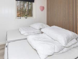 een bed met witte lakens en kussens in een kamer bij Holiday home Aars III in Års