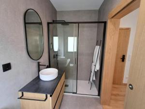 a bathroom with a sink and a shower with a mirror at OPORTO Suites in Moreira